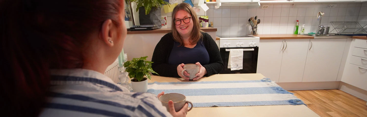 Två unga glada kvinnor vid ett köksbord