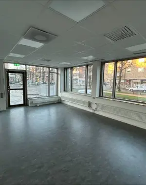 Bild tagen inifrån en lokal med stora skylfönster ut mot gata