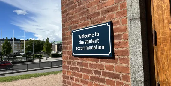 Fasadskylt på studentboendet på högskolans campus, med Drottningtorget i bakgrunden.