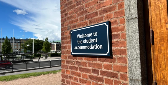 Fasadskylt på studentboendet på högskolans campus, med Drottningtorget i bakgrunden.