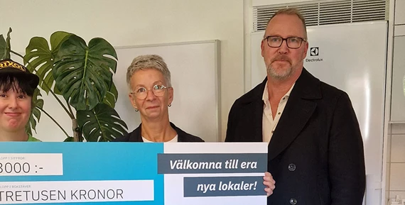 Vid invigningen tog Viola Juric, enhetschef för Slättbergsvägen 180 och Johanna Johansson, en av de boende, emot ett presentkort i stort format från Hans-Åke Erlandsson, Eidars projektledare för renoveringen och anpassningen av lokalerna.