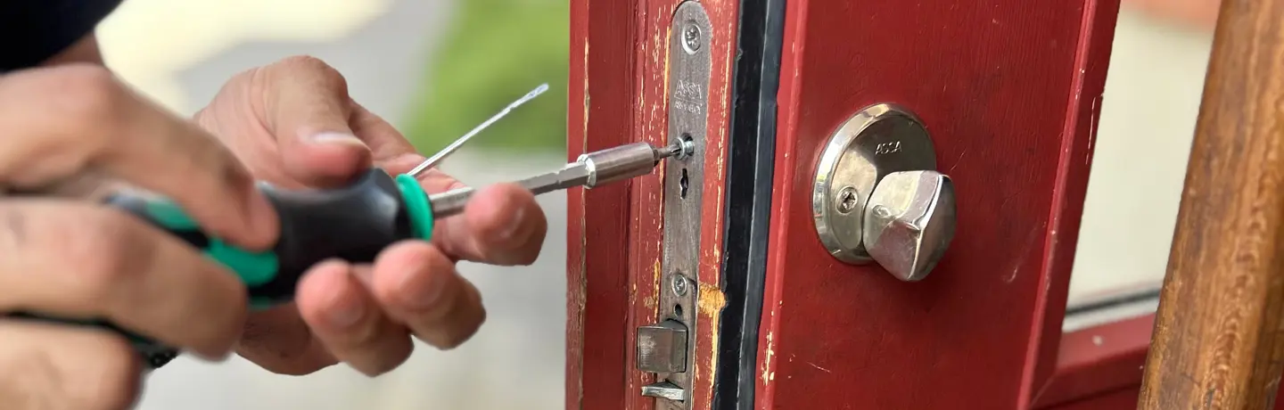 Någon skruvar ut en skruv från en dörr
