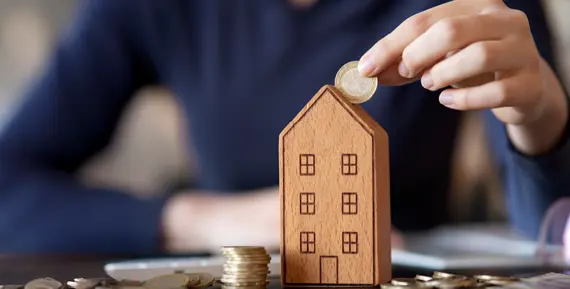 hand som stoppar mynt i spargris i form av höghus