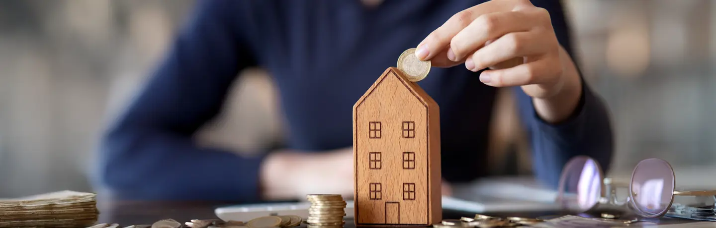 hand som stoppar mynt i spargris i form av höghus