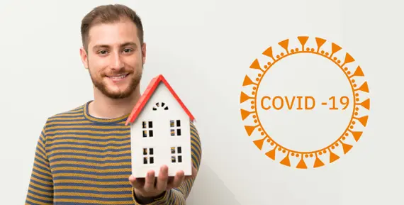 Man som håller ett hus i sin hand, i bakgrunden syns en corona-ikon.