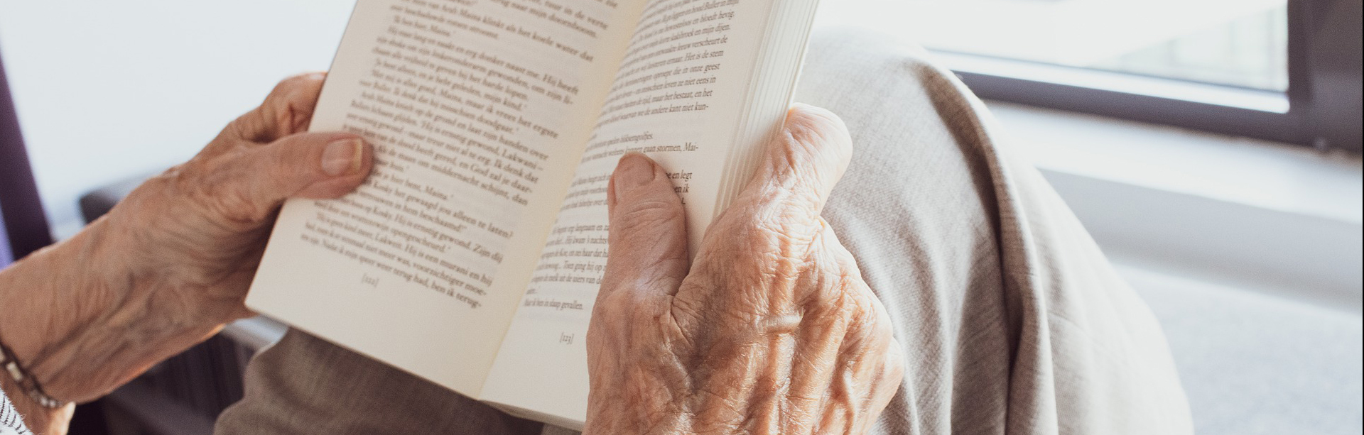 Äldre person som sitter och läser en bok