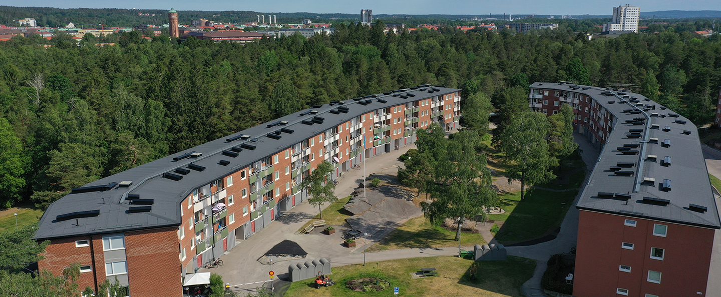 Två trevåningshus som ligger mittemot varandra. Skogen omger i bakgrund och en grön innergård emellan
